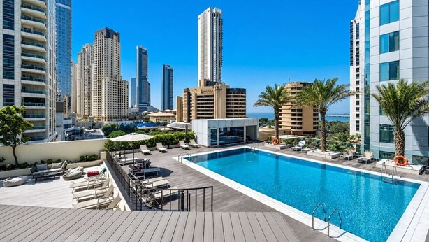 Una piscina en la azotea con sillas de descanso y vistas a edificios altos.