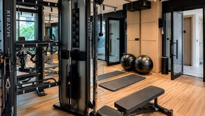 Ein Fitnessraum mit Trainingsgeräten, einer Bank und Trainingsbällen.