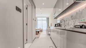 A modern kitchen with a marble countertop, a coffee machine, and a 'Welcome' sign. - HAVN - Studio in Stonehenge Residences, JVC (Dubai)