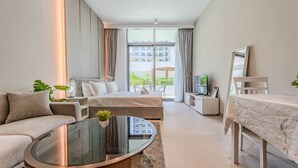 A modern hotel room with a bed, sofa, TV, and a balcony with a view. - HAVN - Studio in Stonehenge Residences, JVC (Dubai)