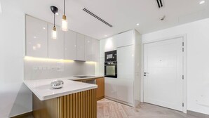 Une cuisine moderne avec des meubles blancs, un îlot central en bois et des luminaires suspendus.