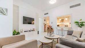 A modern living room with a sofa, a coffee table, and a TV. - HAVN - 1 Bedroom in Azure, 5 mins to DMCC metro (Dubai)