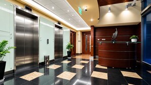 A modern lobby with elevators, a reception desk, and potted plants. - HAVN - 1 Bedroom in Azure, 5 mins to DMCC metro (Dubai)