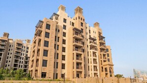 Un immeuble résidentiel à plusieurs étages, doté de balcons, d’un toit plat et surplombant un ciel dégagé.