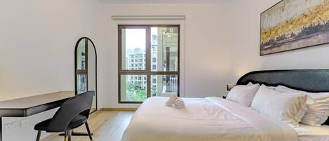 A bedroom with a bed, a desk, a chair, a window, and a painting on the wall.