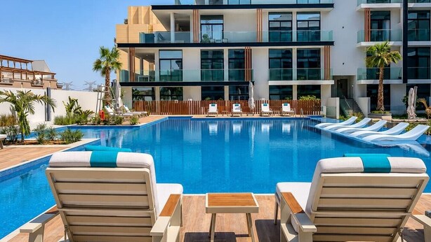 Ein modernes Hotel mit Schwimmbad, Liegestühlen und einer Holzterrasse.