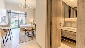 Ein modernes Hotelzimmer mit einem großen Bett, einem Essbereich, einem Badezimmer mit großem Spiegel und Blick auf die Stadt.