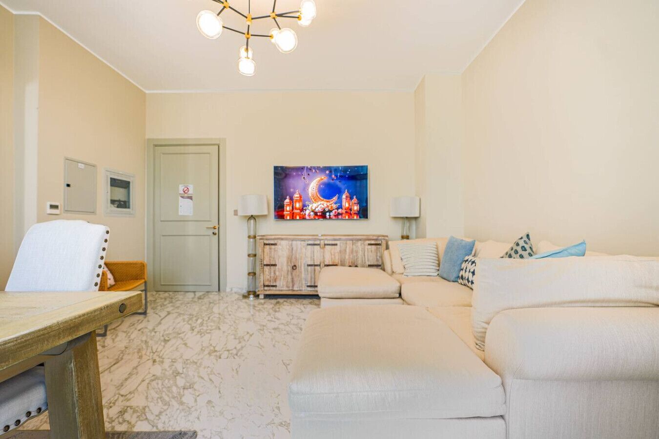 A living room with a sofa, a wooden table, a lamp, a painting, and a door.