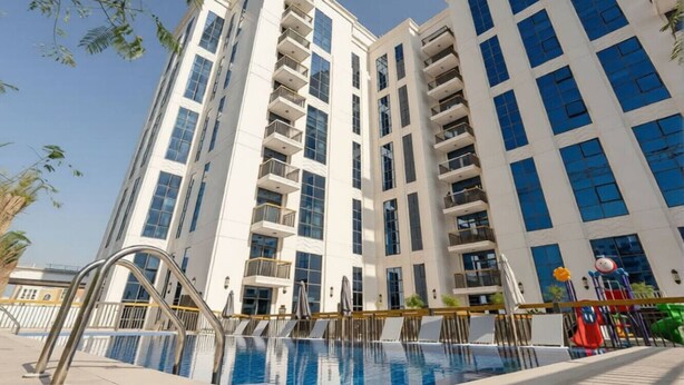 Un edificio moderno con piscina, balcones y cielo despejado.