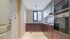 Una cocina con gabinetes de madera oscura, encimera de mármol y electrodomésticos de acero inoxidable.