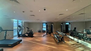 Un gimnasio con cintas de correr, elípticas y pesas libres.