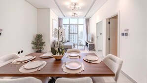Un'elegante sala da pranzo con un tavolo lungo apparecchiato per sei persone, una pianta in vaso e vista sulla città attraverso ampie finestre.