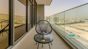 Un balcone con due sedie, un tavolino in vetro e vista sulla città e sulla autostrada.