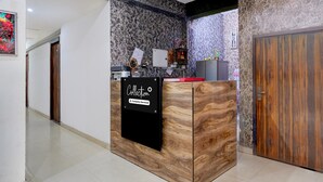 A reception desk with a sign reading 'Collection,' a ceiling fan, and a stone-patterned wall. - Collection O Noida Sector 52 Metro Station (Noida)