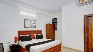 A bedroom with a wooden bed, a nightstand, a wardrobe, and two framed pictures on the wall. - Collection O Noida Sector 52 Metro Station (Noida)