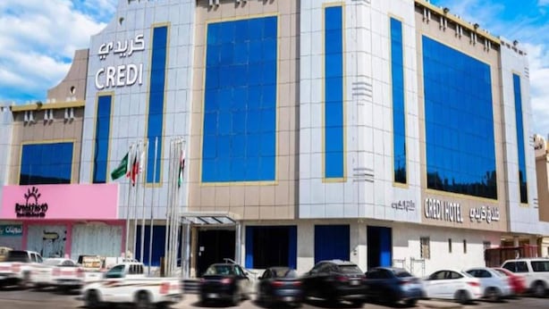 A multi-story building with the signage 'CREDIT HOTEL' and flags. - 2BR Deluxe Family Comfort at Credi Luxury (Riyadh)