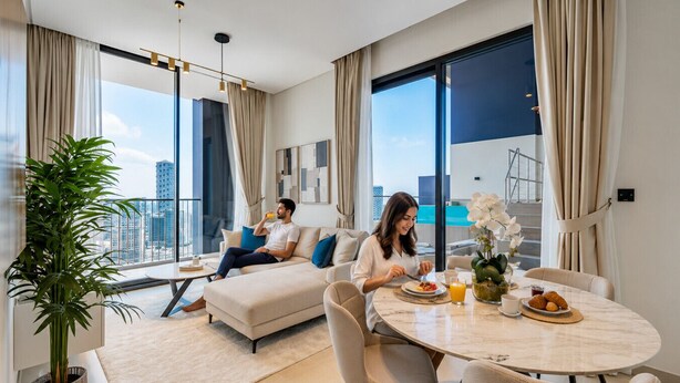 Ein modernes Wohnzimmer mit Sofa, Esstisch und Stühlen, großen Fenstern mit Vorhängen und einer Zimmerpflanze.