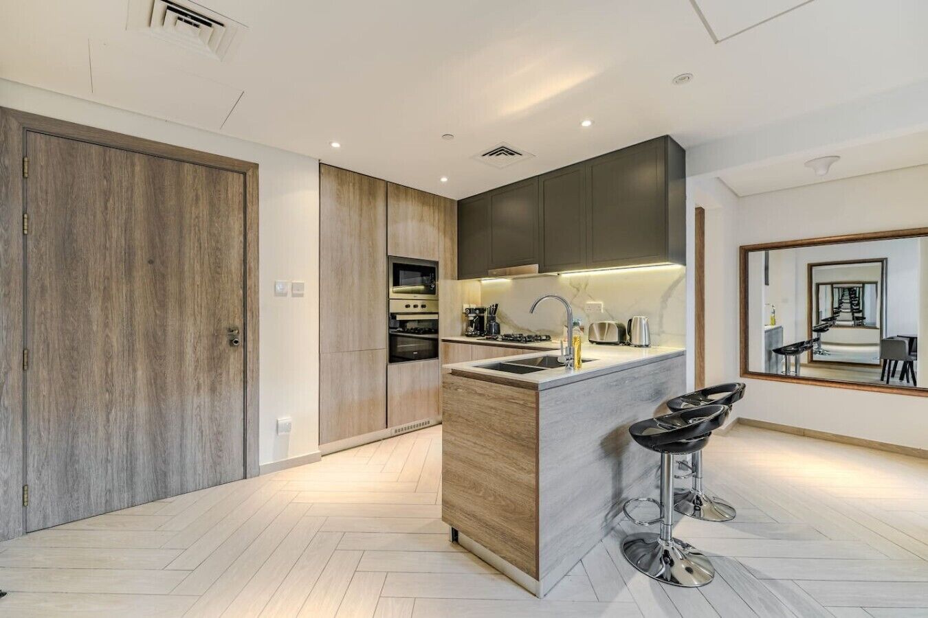 A modern kitchen with a central island, built-in appliances, and a bar stool.