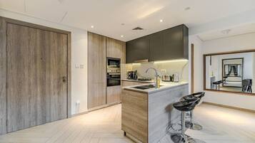 A modern kitchen with a central island, built-in appliances, and a bar stool.