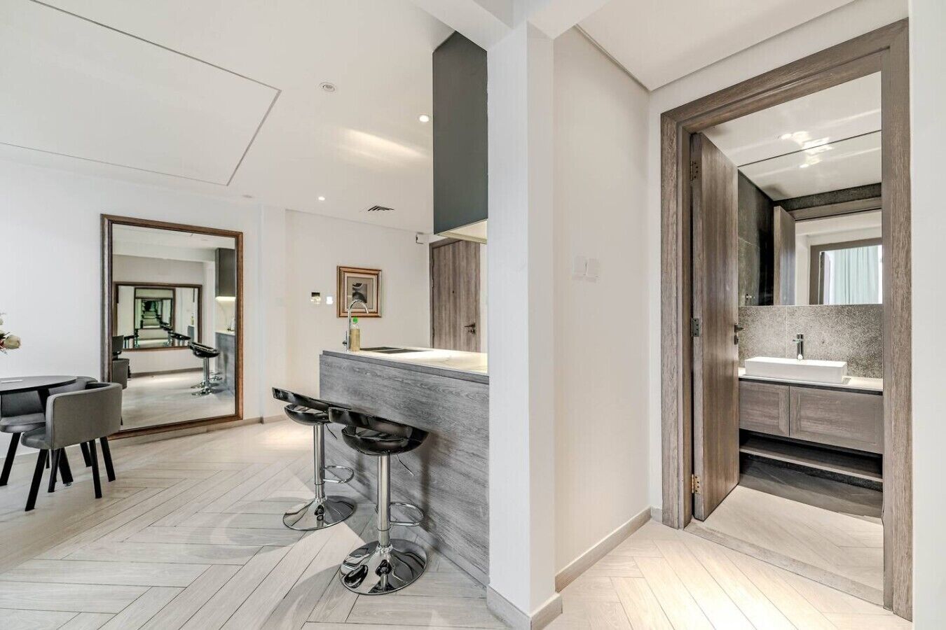 A modern interior with a dining area, a kitchen with a large island, and a bathroom with a wooden vanity.