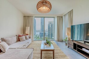 Uma sala de estar moderna com sofá, mesa de centro, televisão e uma grande janela com vista para a cidade.