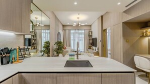 Une cuisine moderne dotée d’un îlot central, d’appareils électroménagers intégrés et d’un coin repas avec une chaise blanche.