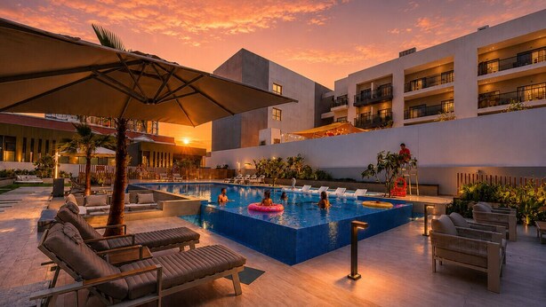 Área de piscina en la azotea con sillones de descanso, piscina y vistas al atardecer.