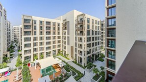 A modern apartment building with multiple floors, balconies, and a central courtyard with a swimming pool. - HAVN - 1 Bed in Cedar 3, Creek Harbour (Dubai)