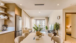 A modern hotel room with a dining area, kitchen, and a balcony with a city view. - HAVN - 1 Bed in Cedar 3, Creek Harbour (Dubai)