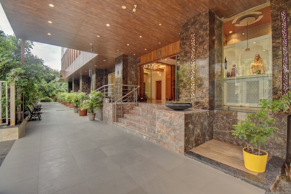 Un edificio moderno con fachada de piedra, techo de madera y una escalera que lleva a la entrada.