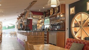 Un interior de restaurante con barra de madera, zona de asientos y exhibición de vinos.