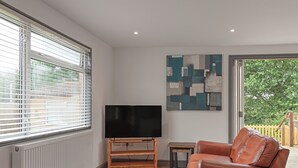 Una sala de estar con televisor, sofás de cuero, una mesa de centro de madera y un cuadro en la pared.