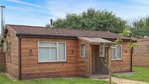 A wooden cabin with a tiled roof, a small porch, and a grassy yard. - 2 bedroom accommodation in Westward Ho! (Westward Ho!)