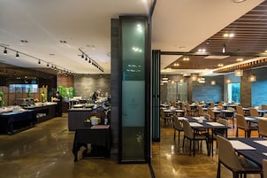 Un restaurante moderno con una zona de bar, mesas de comedor y un chef preparando comida.
