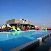 Una piscina con sillas de descanso y un edificio que indica 'K-Tree Jeju Seongsan'.