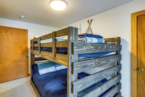 Un lit superposé avec une structure en bois et une tête de lit ornée d’un motif ondulé.