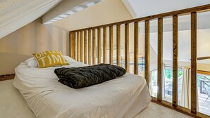 Ein Schlafzimmer mit einem Bett, einer Holzlattung als Raumteiler und Blick auf einen Balkon.