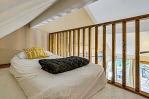 Ein Schlafzimmer mit einem Bett, einer Holzlattung als Raumteiler und Blick auf einen Balkon.