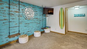 Ein Zimmer mit einem Schild, das einen rustikalen Rückzugsort anzeigt, einem Fernseher, einer Surfbrett-Dekoration und einem Handtuchhalter.