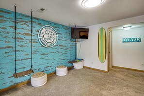 Ein Zimmer mit einem Schild, das einen rustikalen Rückzugsort anzeigt, einem Fernseher, einer Surfbrett-Dekoration und einem Handtuchhalter.