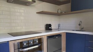 A modern kitchen with a built-in oven, dishwasher, and a coffee maker on the countertop.