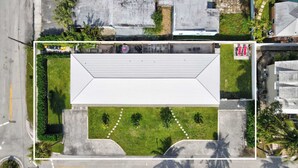 An aerial view of a building with a flat roof, surrounded by greenery and a paved area. - Marina Row 3 Beach, Shops (Delray Beach)