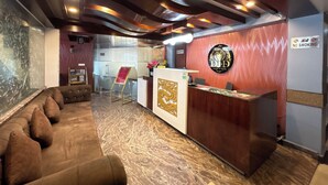 Un espace d’accueil d’hôtel comprenant un comptoir de réception, un coin salon avec des canapés et un panneau indiquant « Il est interdit de fumer ».