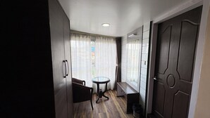 Une pièce avec un plancher en bois, une table ronde, une chaise, une armoire et une porte.