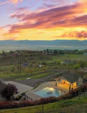 Zona residencial con una casa que tiene piscina, rodeada por un patio cercado y vistas a montañas distantes.