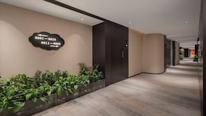 Un pasillo moderno con señalización direccional, una pared con plantas y un techo curvo.