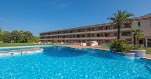 Ein Hotel mit Schwimmbad, mehreren Balkonen und einem gepflegten Rasen.