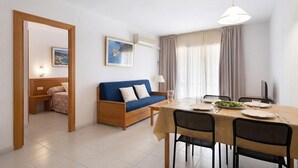 Um quarto com uma cama, um sofá azul, uma mesa de jantar com cadeiras e um quadro na parede.
