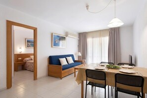 Ein Zimmer mit einem Bett, einem blauen Sofa, einem Esstisch mit Stühlen und einem Bild an der Wand.