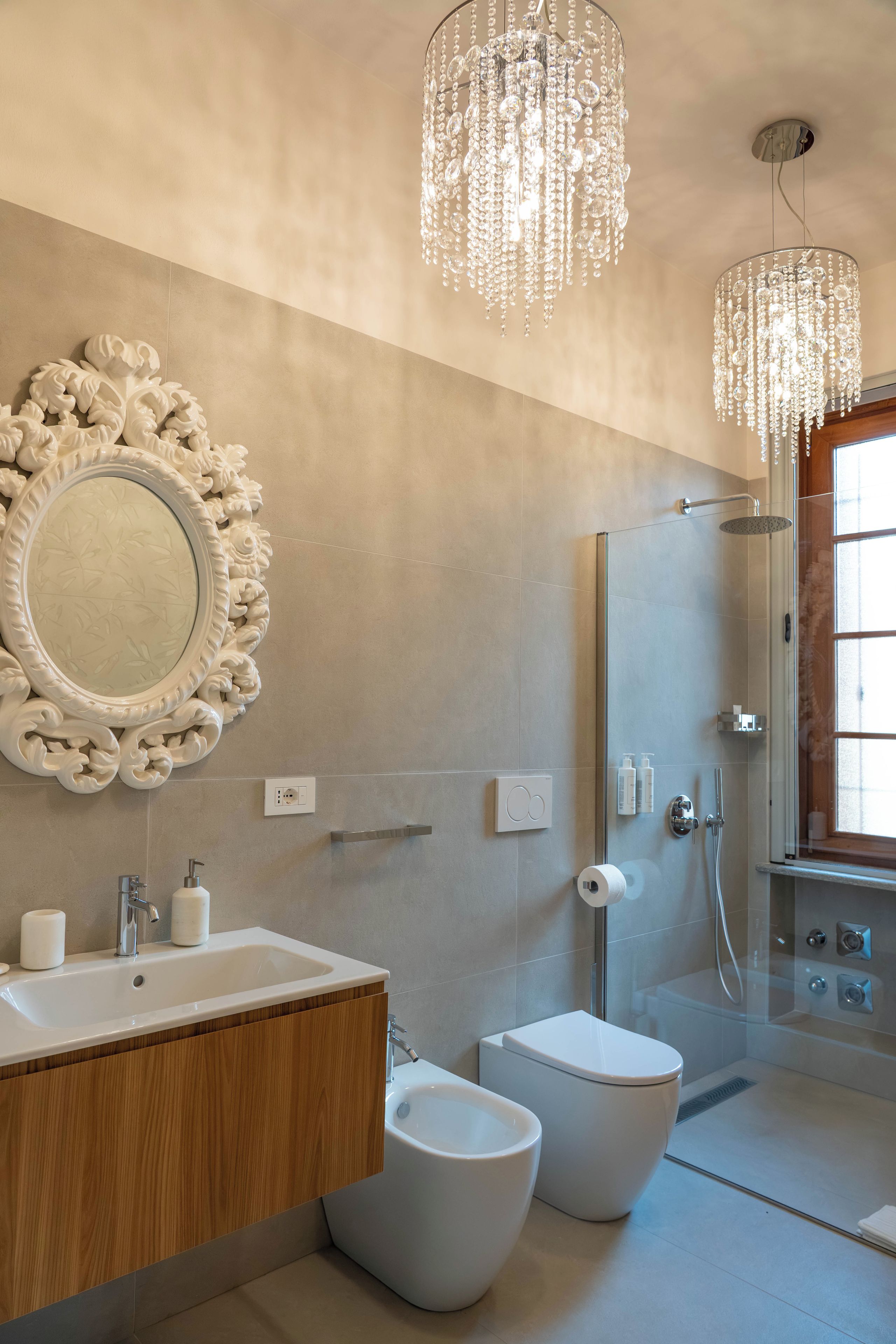 Ein modernes Badezimmer mit einem großen Spiegel, zwei Toiletten, einem Waschbecken und einer Dusche.